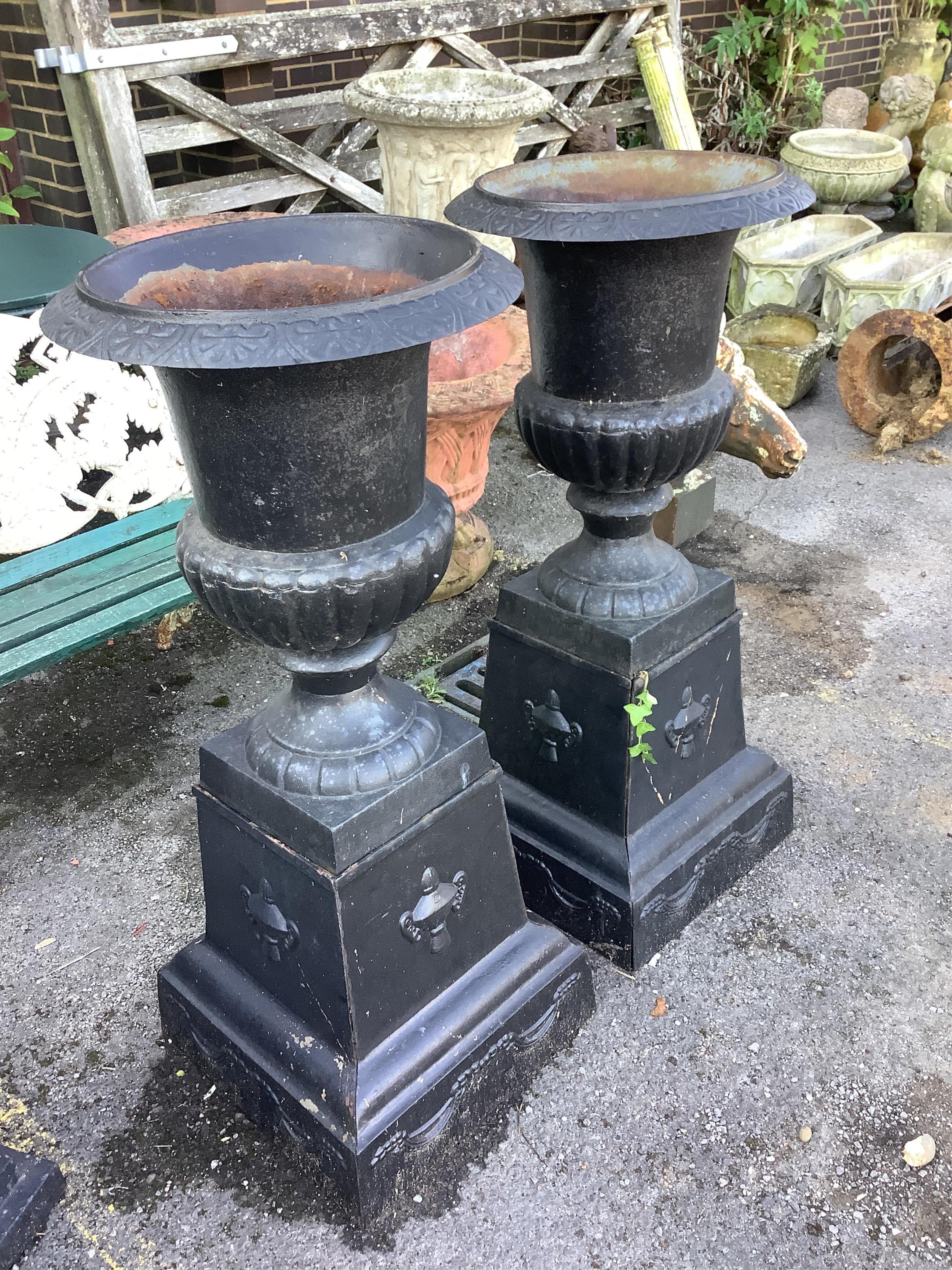 A pair of Victorian style black painted cast iron campana shaped garden urns, on square plinths, diameter 50cm, height 113cm. Condition - fair